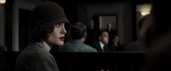 Movie still from “Changeling” (2008), directed by Clint Eastwood – A woman in a hat and a brown hat in front of a group of people; Close Up shot, Over the shoulder angle