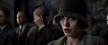 Movie still from “Changeling” (2008), directed by Clint Eastwood – A woman wearing a hat with a man in the background; Close Up shot, Over the shoulder angle