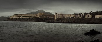 Movie still from “Changeling” (2008), directed by Clint Eastwood – A lighthouse in front of a large building on the shore; Extreme Wide shot, High angle