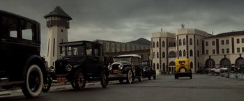 Movie still from “Changeling” (2008), directed by Clint Eastwood – A group of old cars driving down a street; Extreme Wide shot, Low angle