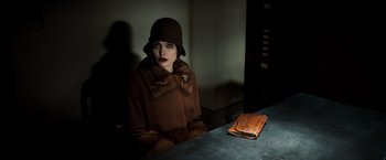 Movie still from “Changeling” (2008), directed by Clint Eastwood – A woman sitting at a table with a book; Medium shot, Low angle