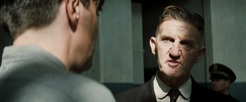 Movie still from “Changeling” (2008), directed by Clint Eastwood – A man wearing a suit and tie talking to another man in a suit; Close Up shot, Over the shoulder angle