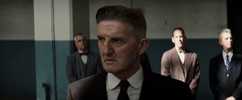 Movie still from “Changeling” (2008), directed by Clint Eastwood – An older man in a suit and tie looking to his left; Close Up shot, Over the shoulder angle
