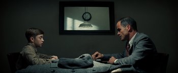 Movie still from “Changeling” (2008), directed by Clint Eastwood – A man sitting at a table in front of a television; Medium shot, Over the shoulder angle