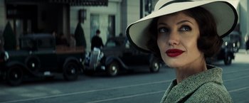 Movie still from “Changeling” (2008), directed by Clint Eastwood – A woman with a hat and lipstick standing in front of a car; Close Up shot, Over the shoulder angle
