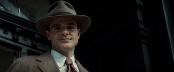 Movie still from “Changeling” (2008), directed by Clint Eastwood – A man wearing a hat and a suit and tie; Close Up shot, Low angle