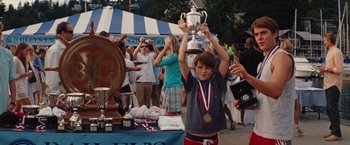 Movie still from “Charlie St. Cloud” (2010), directed by Burr Steers – A young boy holding a trophy in front of a crowd; Medium shot, Low angle
