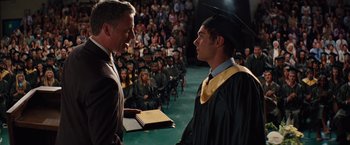 Movie still from “Charlie St. Cloud” (2010), directed by Burr Steers – A man in a graduation cap and gown is handing a diploma to another man; Medium shot, Over the shoulder angle