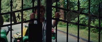 Movie still from “Charlie St. Cloud” (2010), directed by Burr Steers – A man standing behind a metal fence looking out at the trees; Medium shot, Low angle