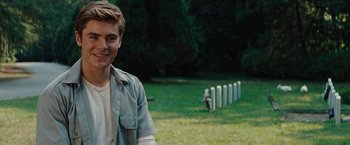 Movie still from “Charlie St. Cloud” (2010), directed by Burr Steers – A man standing in front of a row of white tombstones in a field; Close Up shot, Over the shoulder angle