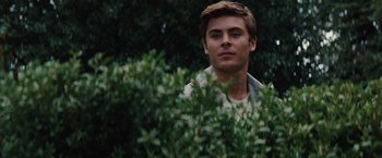 Movie still from “Charlie St. Cloud” (2010), directed by Burr Steers – A man standing next to a bush with trees in the background; Medium shot, Over the shoulder angle