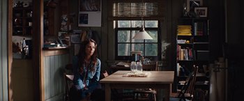 Movie still from “Charlie St. Cloud” (2010), directed by Burr Steers – A woman sitting at a wooden table in front of a window; Wide shot, Over the shoulder angle