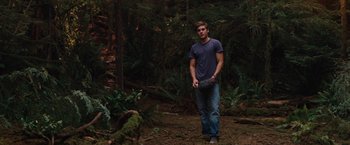 Movie still from “Charlie St. Cloud” (2010), directed by Burr Steers – A man standing in the middle of a forest holding a frisbee; Wide shot, Over the shoulder angle