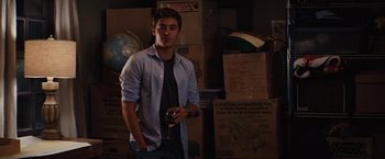 Movie still from “Charlie St. Cloud” (2010), directed by Burr Steers – A man standing in a room holding a beer; Medium shot, Over the shoulder angle