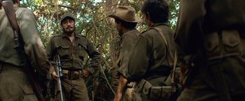 Movie still from “Che: Part One” (2008), directed by Steven Soderbergh – A group of men standing next to each other in the woods; Medium shot, Over the shoulder angle