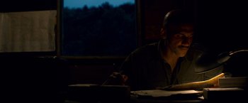 Movie still from “Che: Part One” (2008), directed by Steven Soderbergh – A man sitting at a table writing on a piece of paper; Medium shot, Low angle
