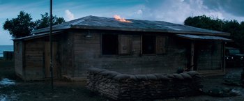 Movie still from “Che: Part One” (2008), directed by Steven Soderbergh – A building that has a fire coming out of it; Extreme Wide shot, Low angle