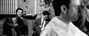 Movie still from “Che: Part One” (2008), directed by Steven Soderbergh – A black and white photo of a man in a suit and tie; Medium shot, Over the shoulder angle