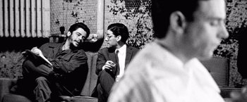 Movie still from “Che: Part One” (2008), directed by Steven Soderbergh – A black - and - white photo of two men sitting next to each other; Medium shot, Over the shoulder angle