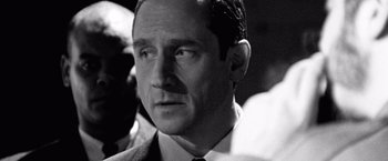 Movie still from “Che: Part One” (2008), directed by Steven Soderbergh – Black and white photograph of a man in a suit and tie; Close Up shot, Over the shoulder angle