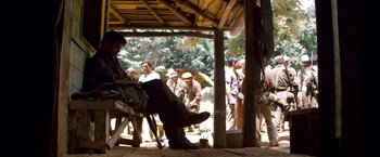 Movie still from “Che: Part One” (2008), directed by Steven Soderbergh – A group of people standing around a wooden structure; Wide shot, High angle