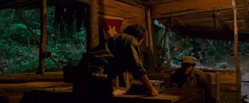 Movie still from “Che: Part One” (2008), directed by Steven Soderbergh – A man standing on top of a wooden table; Wide shot, Over the shoulder angle
