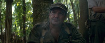 Movie still from “Che: Part One” (2008), directed by Steven Soderbergh – A person wearing a hat near a tree; Close Up shot, Over the shoulder angle