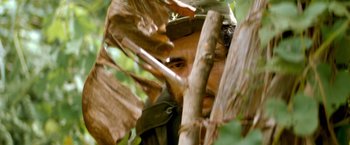 Movie still from “Che: Part One” (2008), directed by Steven Soderbergh – A man with a hat on looking through the branches of a tree; Close Up shot, Low angle