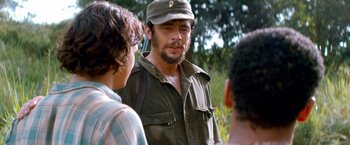 Movie still from “Che: Part One” (2008), directed by Steven Soderbergh – A group of people standing next to each other in a field; Close Up shot, Over the shoulder angle