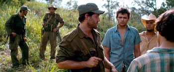 Movie still from “Che: Part One” (2008), directed by Steven Soderbergh – A group of men standing next to each other on top of a hill; Medium shot, Over the shoulder angle
