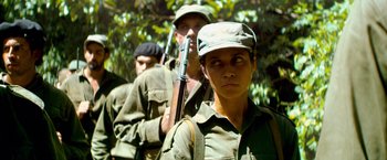 Movie still from “Che: Part One” (2008), directed by Steven Soderbergh – A group of people with guns in a forest; Medium shot, Low angle