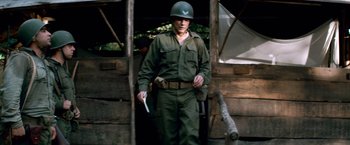 Movie still from “Che: Part One” (2008), directed by Steven Soderbergh – A man in a military uniform holding a knife in his hand; Medium shot, Low angle