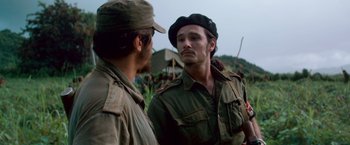 Movie still from “Che: Part One” (2008), directed by Steven Soderbergh – A man in a hat is talking to another man in a field; Close Up shot, Over the shoulder angle