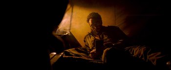 Movie still from “Che: Part One” (2008), directed by Steven Soderbergh – A man sitting on a couch looking at a tablet; Medium shot, High angle
