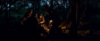 Movie still from “Che: Part One” (2008), directed by Steven Soderbergh – A group of people gathered around a campfire at night; Wide shot, High angle