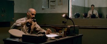 Movie still from “Che: Part One” (2008), directed by Steven Soderbergh – A man sitting at a desk writing on a piece of paper; Medium shot, Low angle