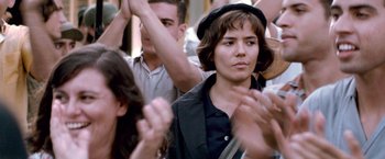 Movie still from “Che: Part One” (2008), directed by Steven Soderbergh – A group of people clapping in a crowd of people; Close Up shot, Over the shoulder angle