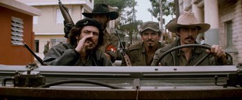 Movie still from “Che: Part One” (2008), directed by Steven Soderbergh – A group of men standing next to each other on a street; Medium shot, Low angle