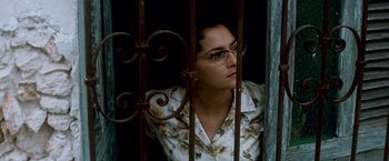 Movie still from “Che: Part One” (2008), directed by Steven Soderbergh – A woman with glasses standing behind a metal gate; Close Up shot, Low angle