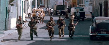 Movie still from “Che: Part One” (2008), directed by Steven Soderbergh – A group of men are walking down the street; Wide shot, High angle