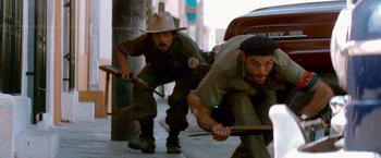Movie still from “Che: Part One” (2008), directed by Steven Soderbergh – A couple of people that are on the sidewalk; Medium shot, Low angle