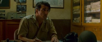 Movie still from “Che: Part One” (2008), directed by Steven Soderbergh – A man sitting at a table with a laptop; Medium shot, Over the shoulder angle