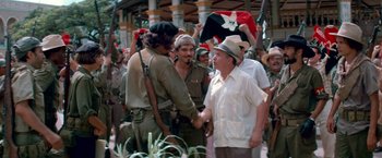 Movie still from “Che: Part One” (2008), directed by Steven Soderbergh – A group of men shaking hands in front of a crowd of onlookers; Medium shot, Over the shoulder angle