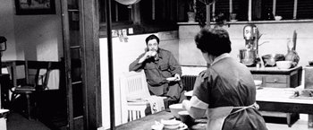 Movie still from “Che: Part One” (2008), directed by Steven Soderbergh – A man sitting at a table with a plate of food in front of him; Medium shot, Over the shoulder angle
