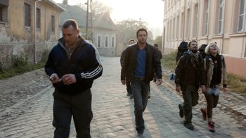 Movie still from “Chernobyl Diaries” (2012), directed by Bradley Parker – A group of men walking down a brick street; Wide shot, Over the shoulder angle