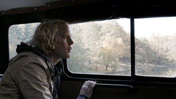 Movie still from “Chernobyl Diaries” (2012), directed by Bradley Parker – A woman looking out of a window on a train; Medium shot, Over the shoulder angle