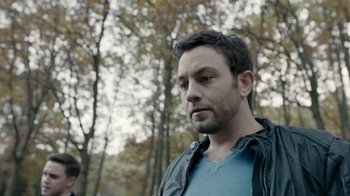 Movie still from “Chernobyl Diaries” (2012), directed by Bradley Parker – A person wearing a jacket near a forest; Close Up shot, Over the shoulder angle
