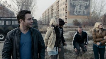 Movie still from “Chernobyl Diaries” (2012), directed by Bradley Parker – A group of people standing in a field near a building; Medium shot, Over the shoulder angle