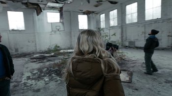 Movie still from “Chernobyl Diaries” (2012), directed by Bradley Parker – A woman is taking a picture in an abandoned building; Wide shot, Over the shoulder angle