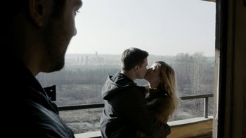 Movie still from “Chernobyl Diaries” (2012), directed by Bradley Parker – A man and a woman kissing in front of a window; Medium shot, Over the shoulder angle